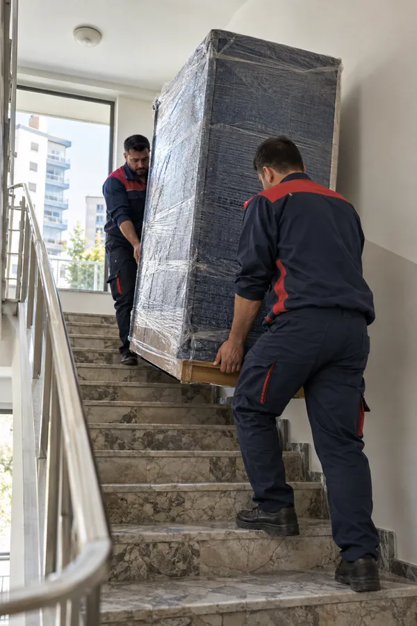 Taşıma ekibi örtülü mobilyayı dikkatle taşıyor
